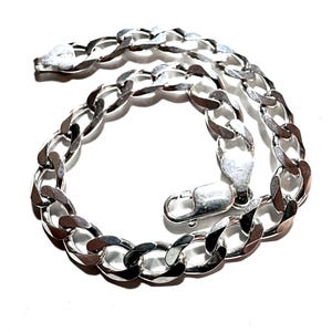 May include: A silver curb chain bracelet with a lobster clasp. The bracelet is made of polished metal and features a series of interconnected, oval links. The clasp is also silver and securely fastens the bracelet.