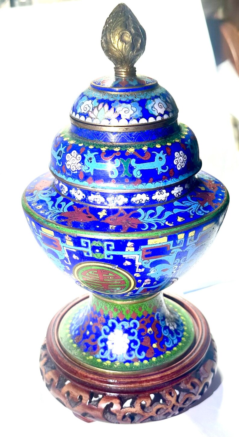 May include: A blue and gold cloisonn&eacute; incense burner with intricate floral and dragon designs. The burner sits on a carved wooden stand.