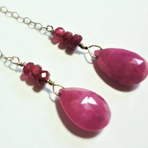 May include: A pair of dangle earrings with pink gemstone drops and smaller pink gemstone accents on the chain.