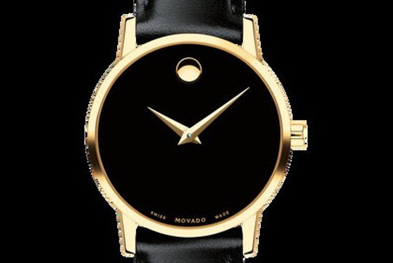 May include: A gold-tone wristwatch with a black face and a single gold hand. The watch face has a small circle at the 12 o'clock position and the words "SWISS MOVADO MADE" printed around the edge.