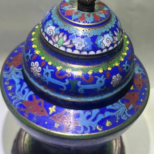 May include: A blue and gold cloisonn&eacute; incense burner with a floral and cloud design. The burner has a wooden base and a gold finial.