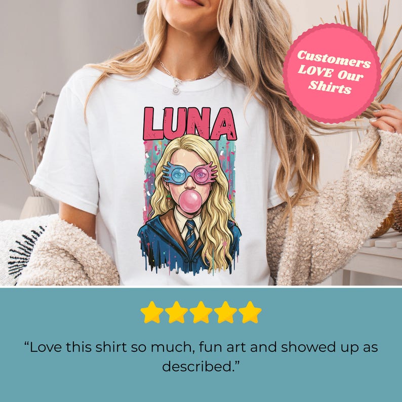 May include: White t-shirt featuring a colorful illustration of a character with the name "LUNA" above. The character is wearing blue and pink glasses and blowing a bubblegum bubble. The shirt has a round neck.