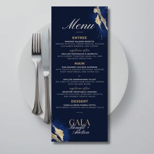 Może przedstawiać: Pionowa karta menu z ciemnoniebieskim tłem i złotymi akcentami, zawierająca tekst Menu, Gala Benefit + Auction oraz listę dań, w tym Smoked Salmon Rosette, Grilled Asparagus, Chicken Supreme i Vanilla Bean Panna Cotta.
