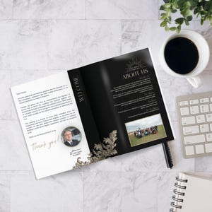 May include: An open black and gold brochure with the text "ABOUT US" and "WELCOME". A cup of coffee, a keyboard, and a notepad are on the marble surface. The brochure features a photo of a group of people.