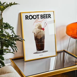 Könnte beinhalten: Ein gerahmtes Poster mit einer Vintage-Illustration eines Root-Beer-Floats. Das Poster trägt den Text "ROOT BEER float" in schwarzen Buchstaben und "EST. 1983" in kleineren Buchstaben.