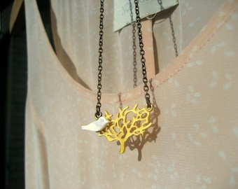 Un pájaro blanco del árbol. Un árbol chapado en oro mate y un pajarito en sus ramas, un romántico collar de latón con encanto.