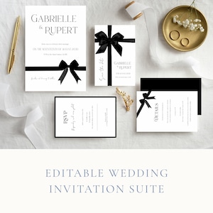 Może przedstawiać: Zestaw zaproszeń ślubnych o minimalistycznym designie. Zestaw zawiera karty zaproszeń, karty RSVP i karty ze szczegółami. Każda karta jest biała z czarnym tekstem i czarną wstążką. Obecny jest również złoty długopis, złota taca z pierścionkami i biała wstążka.
