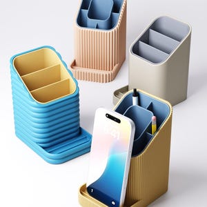 May include: Four colorful desk organizers in blue, tan, beige, and yellow. Each organizer has multiple compartments for pens, pencils, and other office supplies. One organizer holds a smartphone. The organizers have a modern, minimalist design.