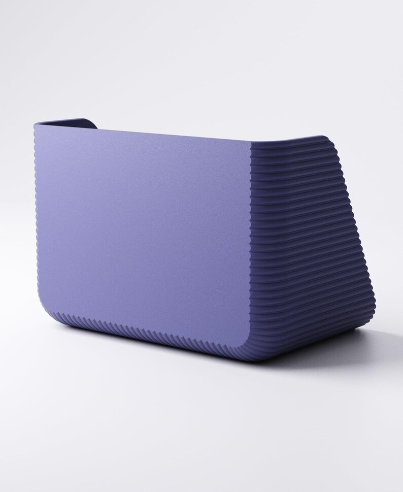 May include: A modern, rectangular planter in a muted purple hue. The planter has a smooth front and a textured, ridged design on the sides, creating a contrast in texture. The overall shape is slightly trapezoidal, with a small lip at the top.