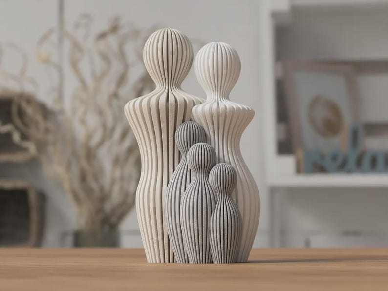 Puede incluir: Un conjunto de esculturas familiares con un dise&ntilde;o moderno. El conjunto incluye dos figuras grandes y tres m&aacute;s peque&ntilde;as, todas en una paleta de colores neutros de blanco y gris. Las figuras tienen un patr&oacute;n de rayas verticales.