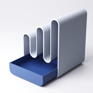 May include: A modern, minimalist desk organizer in shades of blue and white. The design features a wavy, vertical structure with a pull-out drawer. The exterior has a ribbed texture, and the drawer is a solid, deep blue.