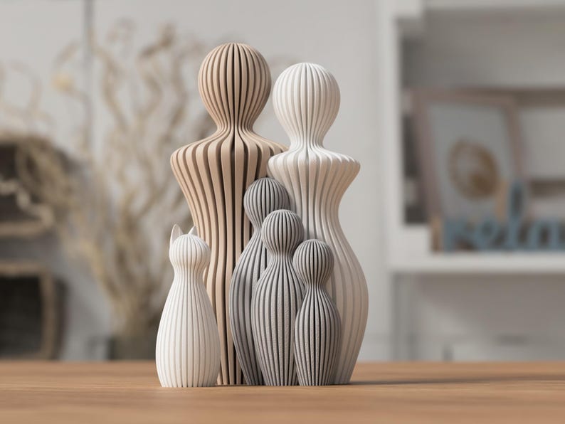 Puede incluir: Colecci&oacute;n de figuras de madera de varios tama&ntilde;os y colores. Las figuras incluyen un gato, dos figuras altas y varias figuras m&aacute;s peque&ntilde;as. Las figuras est&aacute;n hechas de madera marr&oacute;n claro, blanca y gris, con un dise&ntilde;o a rayas.