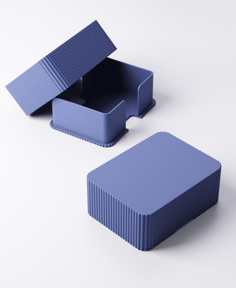 May include: A set of three matching blue-purple desk organizers. The set includes a rectangular box with a lid, and a container with a curved opening. The box and lid have a ribbed texture, while the container has a smooth surface.