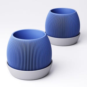 May include: Two blue, ribbed planters with a gray base are displayed against a white background. The planters have a rounded shape with vertical lines, creating a textured effect. The interior of the planters is a solid blue color.