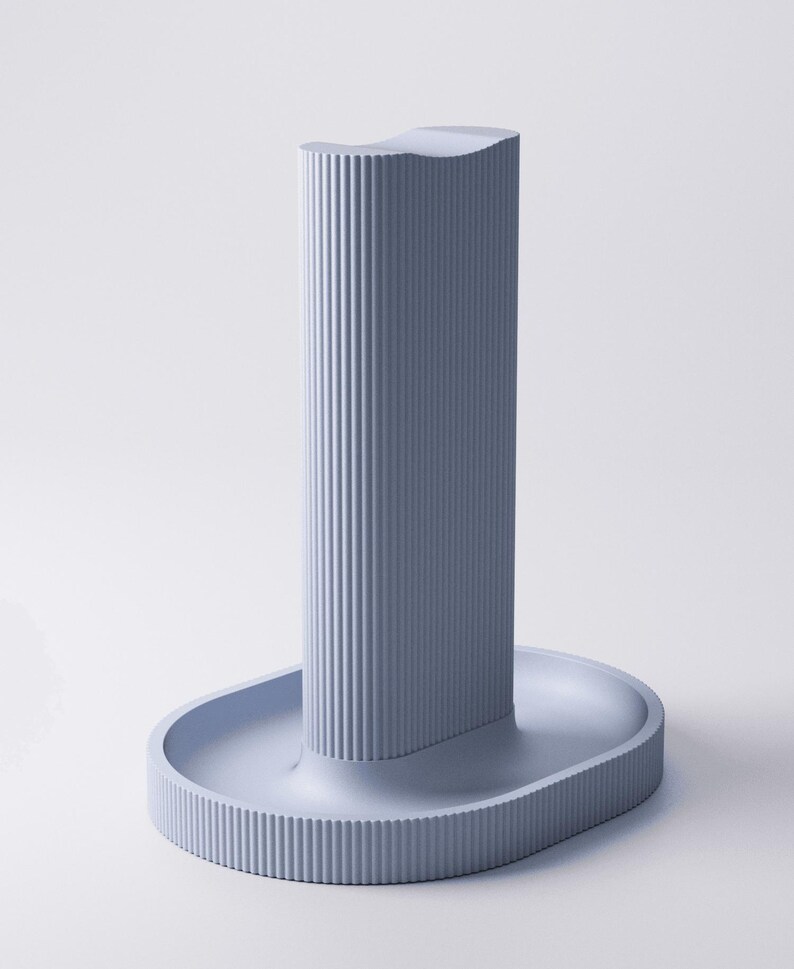 May include: A light blue vertical stand with a ribbed texture on the exterior. The object features a tall, rectangular central column with a concave top, mounted onto an oval-shaped base that also displays a consistent vertical ribbed pattern.