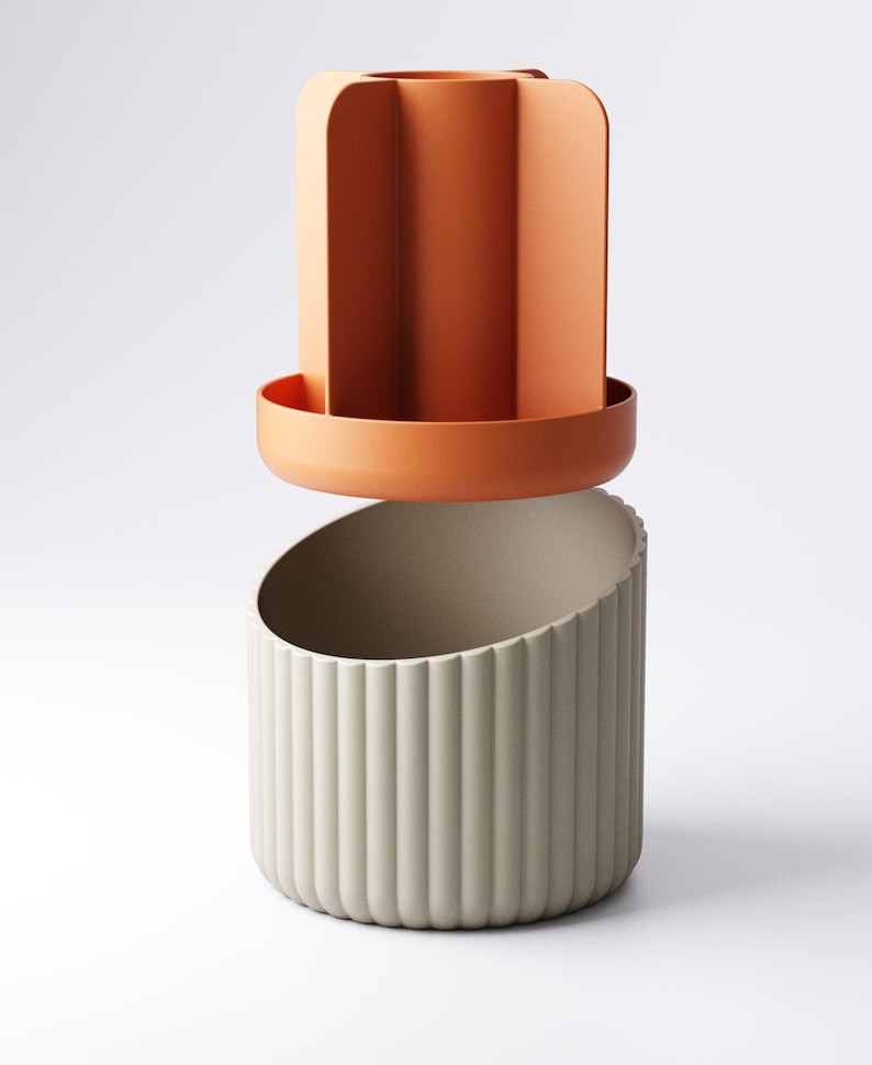 May include: A two-piece decorative container set. The top piece is a terracotta-colored, open-top cylinder with vertical dividers. The bottom piece is a light gray, ribbed, semi-circular container. The pieces are designed to fit together.