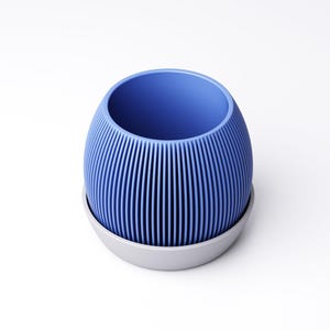 May include: A blue, ribbed, egg-shaped planter with a gray base. The vertical ribs create a textured surface. The planter is designed to hold plants and is suitable for indoor or outdoor use.