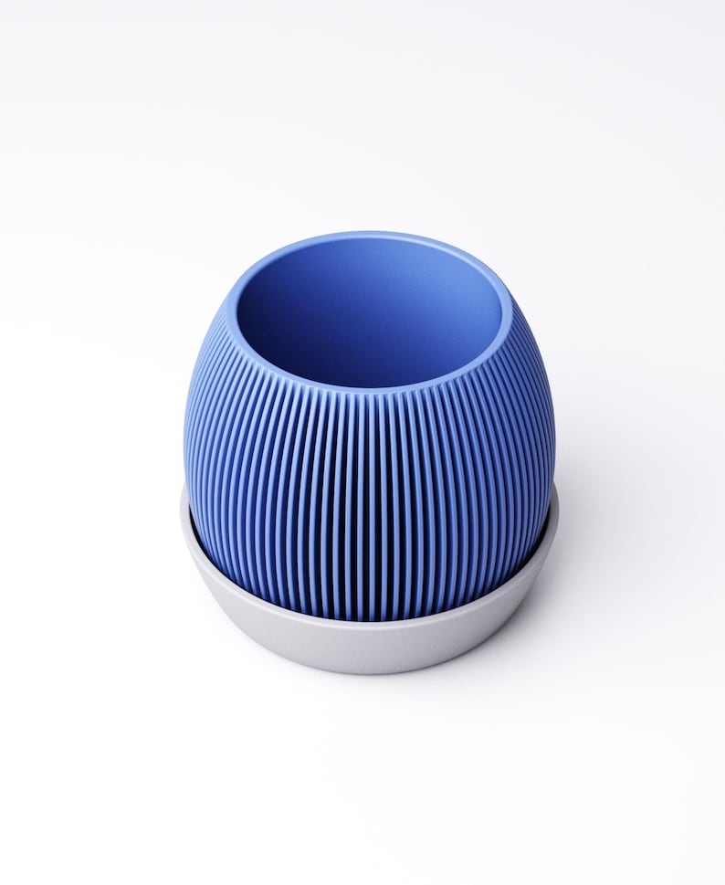 May include: A blue, ribbed, egg-shaped planter with a gray base. The vertical ribs create a textured surface. The planter is designed to hold plants and is suitable for indoor or outdoor use.