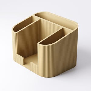 May include: A beige desk organizer with a ribbed texture. The organizer has multiple compartments of varying sizes, including slots for pens and a larger section for other supplies. The design is modern and minimalist, suitable for office or home use.