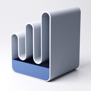 May include: A modern, abstract desk organizer in shades of gray and blue. The design features a series of curved, vertical elements with a ribbed texture, set above a rectangular blue base. The overall aesthetic is minimalist and contemporary.