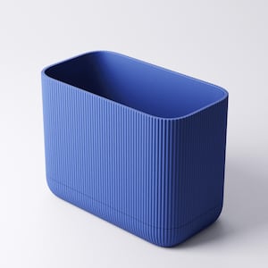 May include: A rectangular storage container in a vibrant blue hue, featuring a distinct vertical ribbed texture along its exterior walls. The object has rounded corners and an open top, presenting a clean, uniform design with a consistent matte finish.
