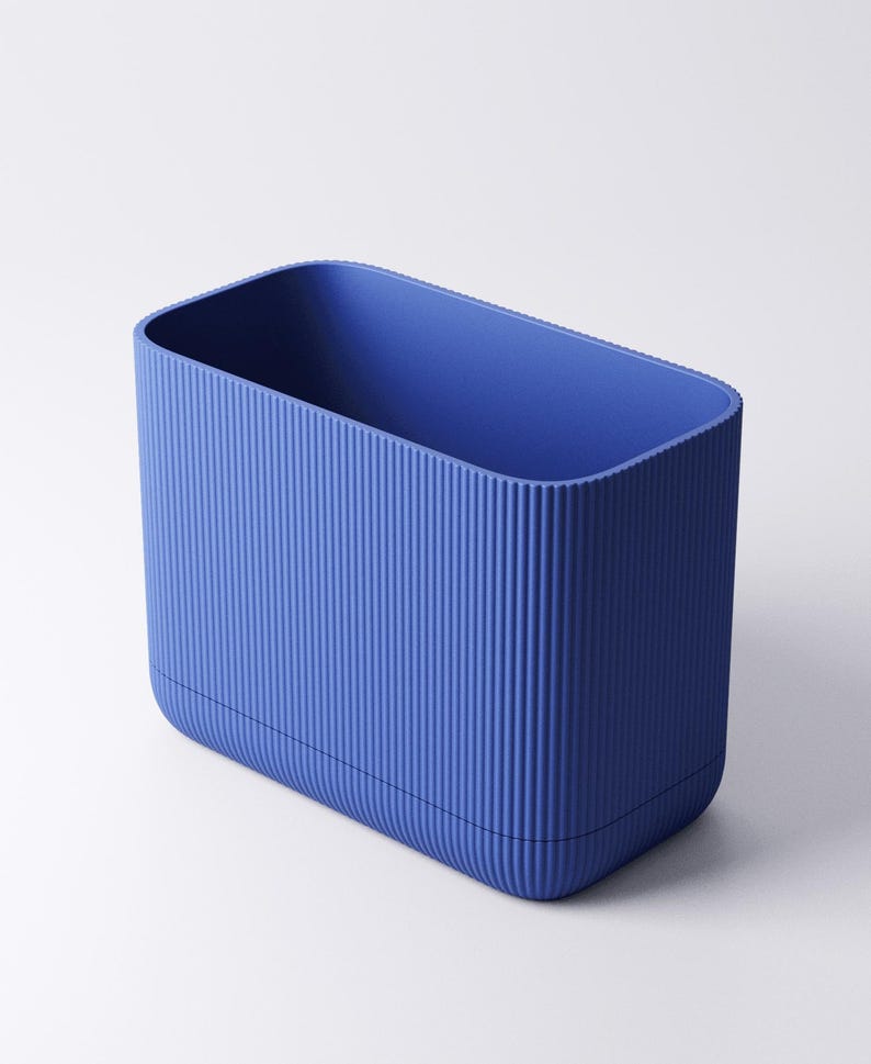 May include: A rectangular storage container in a vibrant blue hue, featuring a distinct vertical ribbed texture along its exterior walls. The object has rounded corners and an open top, presenting a clean, uniform design with a consistent matte finish.