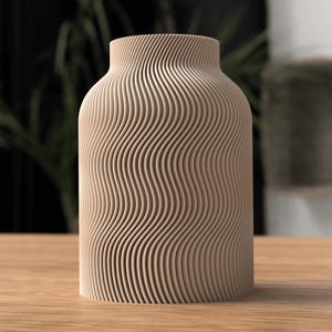 May include: A beige, cylindrical vase with a wavy, grooved pattern. The vase has a wide base and a slightly narrower neck. The design gives the vase a textured appearance. The vase is sitting on a wooden surface.