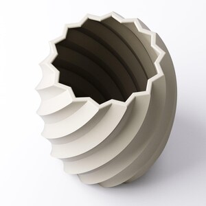 May include: A cream-colored, spiral-shaped vase with a geometric, star-like rim. The vase has a textured, ridged design that wraps around the body. The interior is a darker shade of gray. The vase is set against a white background.