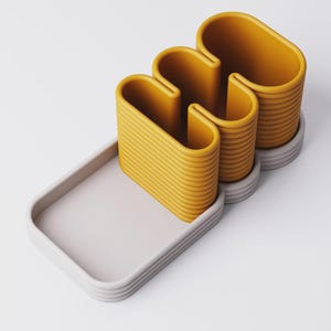 Puede incluir: Conjunto decorativo abstracto moderno. Presenta un objeto ondulado amarillo mostaza con textura acanalada, sobre una bandeja rectangular gris claro. El conjunto incluye una base a juego. Dise&ntilde;o minimalista y contempor&aacute;neo.