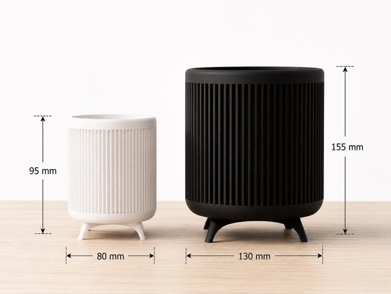 Puede incluir: Dos maceteros cil&iacute;ndricos, uno blanco y otro negro, con detalles acanalados verticales. El macetero blanco mide 9,5 cm de alto y 8 cm de ancho, mientras que el negro mide 15,5 cm de alto y 13 cm de ancho. Ambos tienen tres patas peque&ntilde;as.