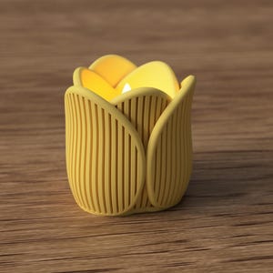 May include: A yellow tulip-shaped candle holder with a lit candle inside. The holder has vertical lines and a petal design. The candle holder is on a wooden surface.