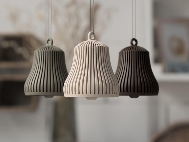 May include: Three pendant lights in a row, each with a bell-shaped shade. The shades are vertically ribbed and come in shades of green, cream, and brown. The lights hang from thin cords.