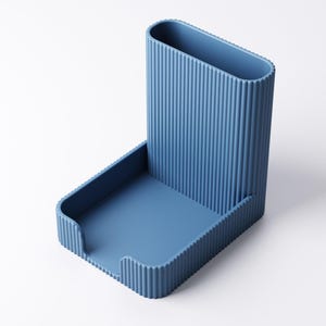 以下が含まれることがあります： 青いデスクオーガナイザー。縦型の溝付きペンホルダーと小さなトレイがあります。オーガナイザーは頑丈な素材で作られており、モダンなデザインです。ペンホルダーの高さは約13cmです。