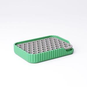 May include: A green and gray silicone ice cube tray. The tray has a rectangular shape with a ribbed green border and a gray honeycomb-patterned interior. A small tab extends from one side.