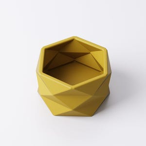 May include: A geometric, yellow planter with a faceted design. The planter has a hexagonal top and a series of diamond-shaped facets that create a modern, angular look. The interior is a matching yellow.