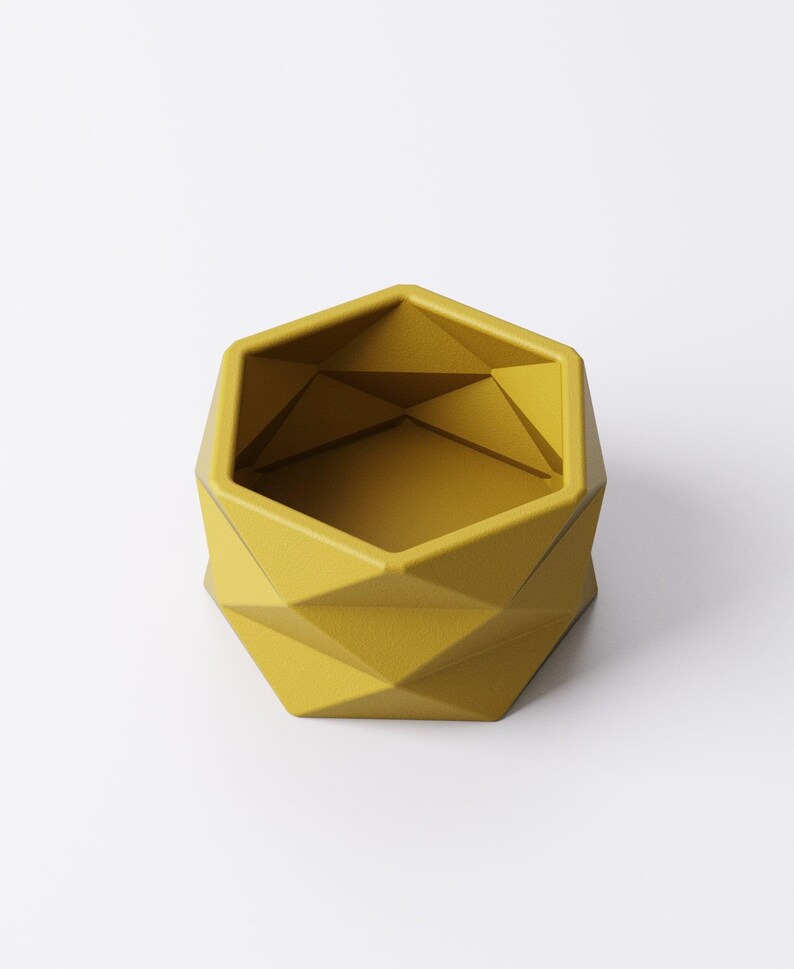 May include: A geometric, yellow planter with a faceted design. The planter has a hexagonal top and a series of diamond-shaped facets that create a modern, angular look. The interior is a matching yellow.