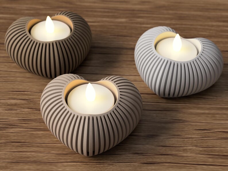 May include: Three heart-shaped candle holders with LED candles. The holders are in shades of gray and beige, with vertical grooves. The candles emit a warm, inviting glow, perfect for home decor and ambiance.
