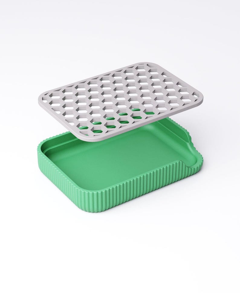 May include: A two-piece container set. The base is a bright green rectangular tray with vertical ridged sides. A gray, honeycomb-patterned lid hovers above the tray. The lid is rectangular with a series of hexagonal cutouts.
