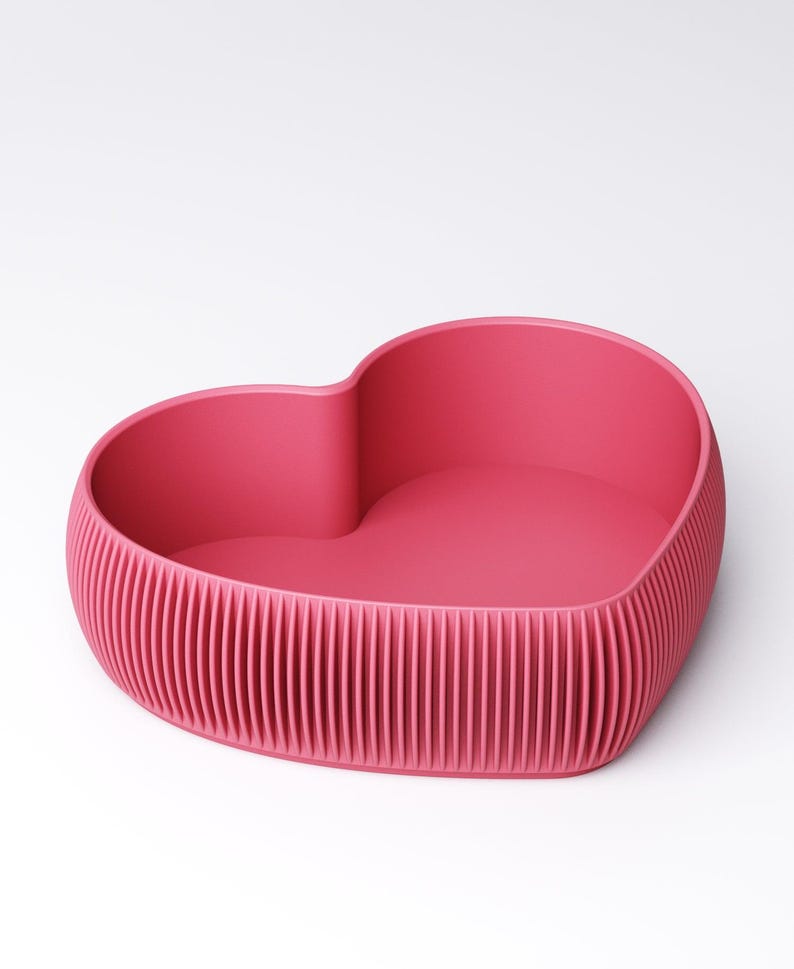 May include: A heart-shaped container in a vibrant pink hue. The container features a textured, ribbed exterior and a smooth interior. The design is modern and minimalist, suitable for various decorative or functional purposes.