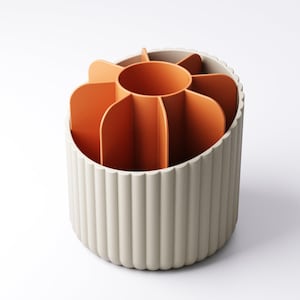 May include: A beige and orange desk organizer with a flower-like design. The organizer has a cylindrical base with vertical ridges and an interior divided into multiple sections. The interior is orange, and the exterior is beige.