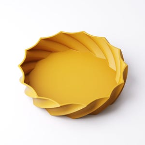 May include: A bright yellow decorative bowl with a unique, swirling design. The bowl has a round, shallow interior and a textured, wave-like exterior. The bowl is made of a solid material and is set against a white background.