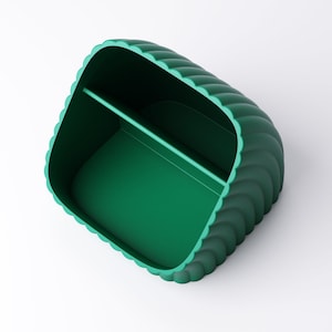 May include: A teal green desk tidy with a scalloped edge design. The organiser has two compartments and a smooth interior. The overall shape is rectangular with rounded corners.