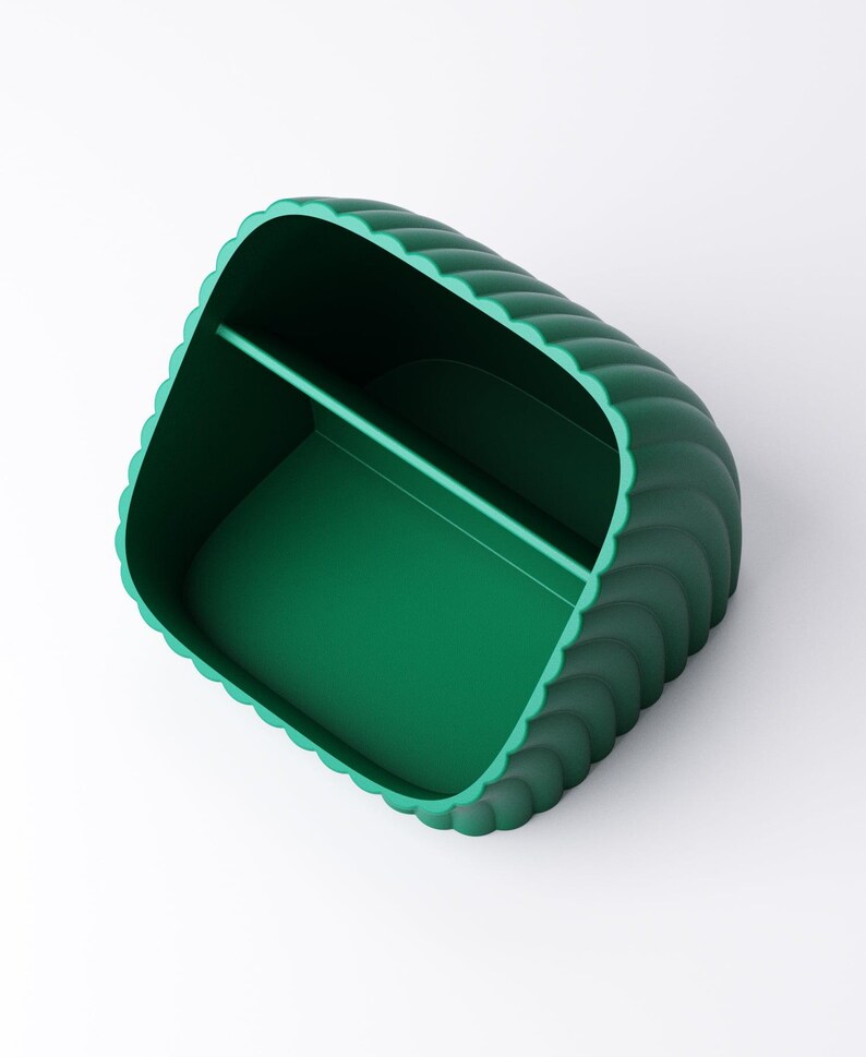 May include: A teal green desk tidy with a scalloped edge design. The organiser has two compartments and a smooth interior. The overall shape is rectangular with rounded corners.