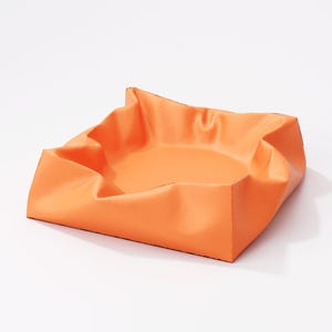 May include: An orange square tray with folded edges. The tray has a smooth, matte finish and a shallow interior. The corners are folded up, creating a unique, sculptural shape. The tray is set against a white background.