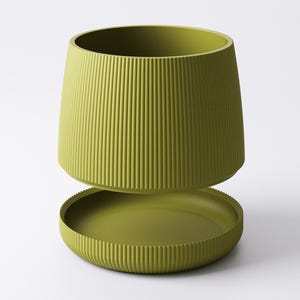 May include: A two-piece, olive-green planter with a ribbed texture. The upper section is a cylindrical pot, and the lower section is a matching saucer. The design is modern and minimalist, suitable for indoor or outdoor use.