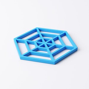 Pu&ograve; includere: Un sottobicchiere geometrico blu brillante a forma esagonale. Il sottobicchiere presenta un design aperto, a forma di ragnatela, con linee intersecanti e motivi triangolari. Il sottobicchiere &egrave; realizzato in materiale solido ed &egrave; su sfondo bianco.