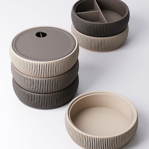 May include: A set of round, stackable storage containers with ribbed exterior walls. The containers come in shades of beige and dark brown, featuring smooth lids and internal dividers in some units, designed for organising small items efficiently.