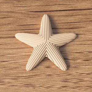 May include: A cream-colored starfish with etched lines, resting on a wooden surface. The five-pointed star has a textured appearance, with each point displaying parallel grooves. The background is a light brown wood grain.