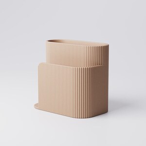 Pu&ograve; includere: Un contenitore rettangolare beige e scanalato con una parte superiore arrotondata e un contenitore pi&ugrave; piccolo e abbinato all'interno. I contenitori hanno una texture verticale ondulata e poggiano su una base piatta. Lo sfondo &egrave; bianco.