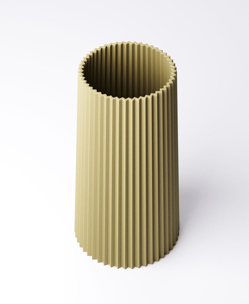 May include: A tall, cylindrical vase in a muted olive green color. The vase features a vertically ribbed design, with a textured surface. The top rim has a decorative, scalloped edge. The vase is set against a plain white background.